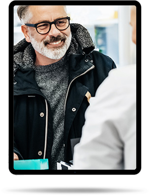 A man smiling and receiving a prescription at a pharmacy